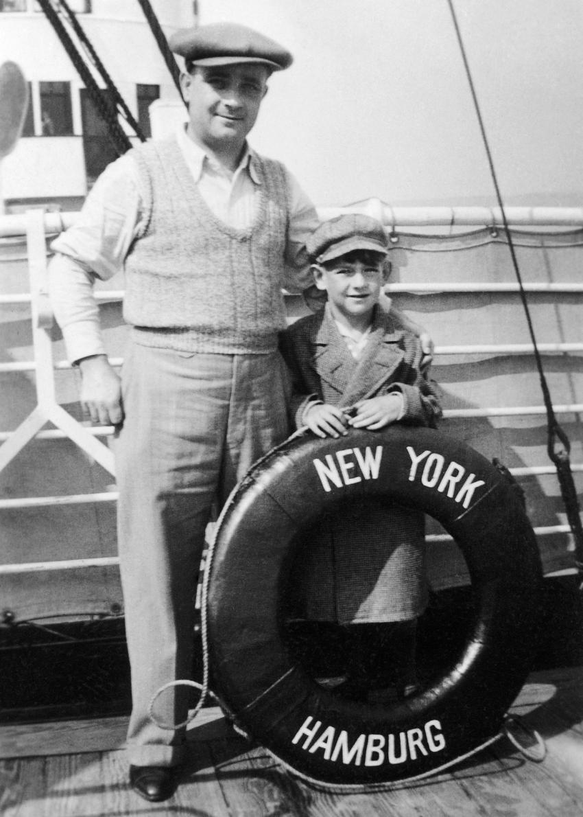 Man and boy on ship deck holding lifesafer with the words New York Hamburg