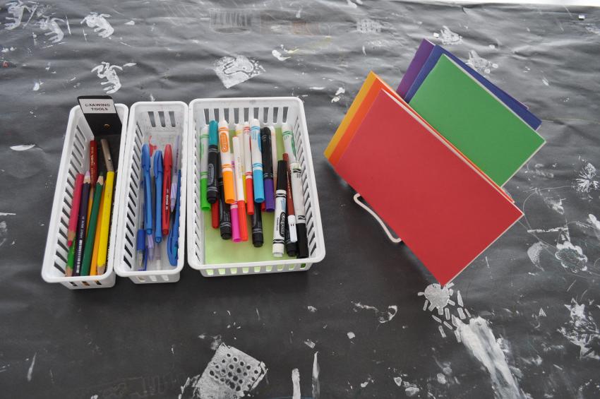 Baskets of drawing tools alongside colorful blank books.