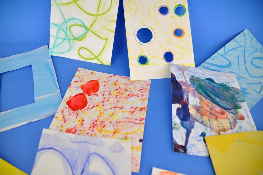 Several brightly colored papers, some with cut out shapes such as circles and a rectangle.