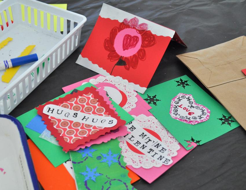 A pile of handmade valentines with cut-paper hearts, stamped phrases of love, and drawings.