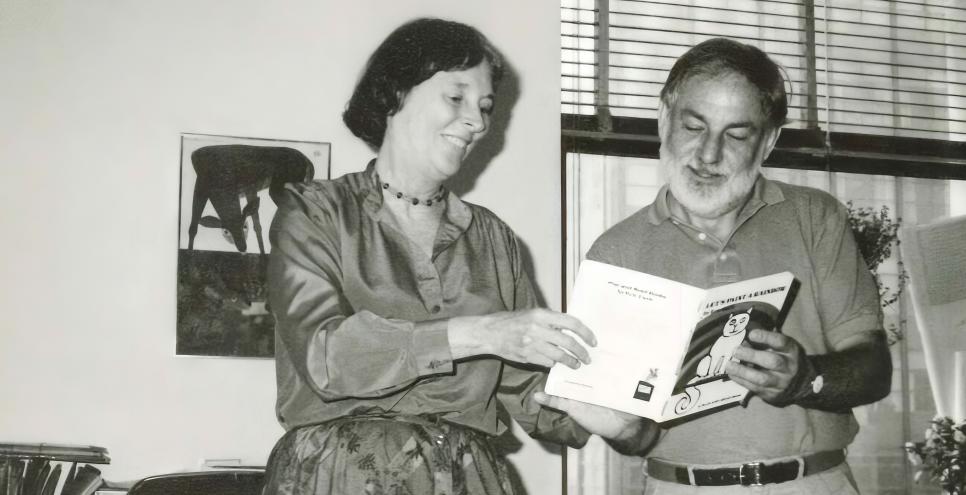 Photograph of two people reading a book together.