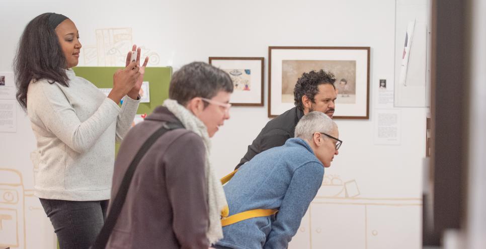 four adults in art gallery looking at art or taking a cell phone photo of art