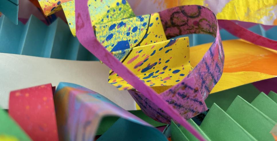 Strips of colorful texturized papers, folded, curled, and bent.