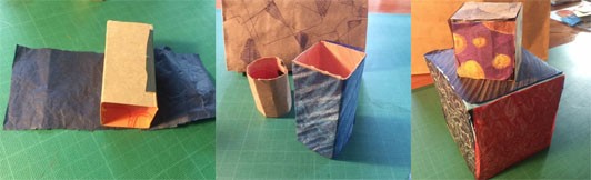 A series of three side by side images. The first shows cardboard folded into a rectangular volume sitting on top of a piece of blue tissue paper. The second shows that volume now covered with the blue tissue paper standing next to a piece of cardboard rolled into a tube. The final image shows two cardboard cubes covered with patterned tissue paper. 