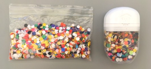 A small plastic bag and candy container both filled with hole punches.