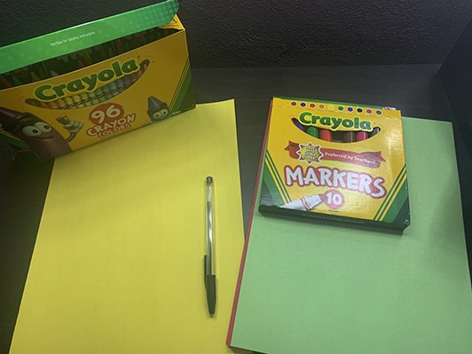 Art materials including construction paper, crayons, and markers. 