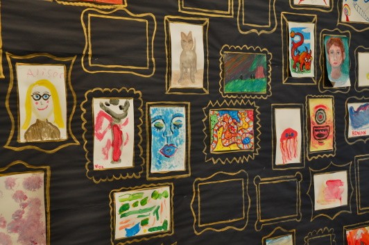 A display wall with painted portraits, each picture has a gold frame drawn around the outside of it.
