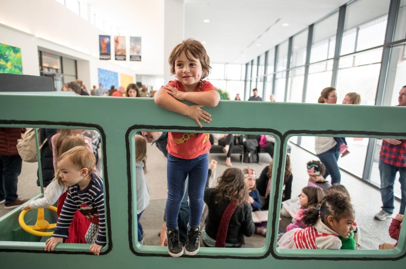 Child standing on Pigeon bus smiling. 