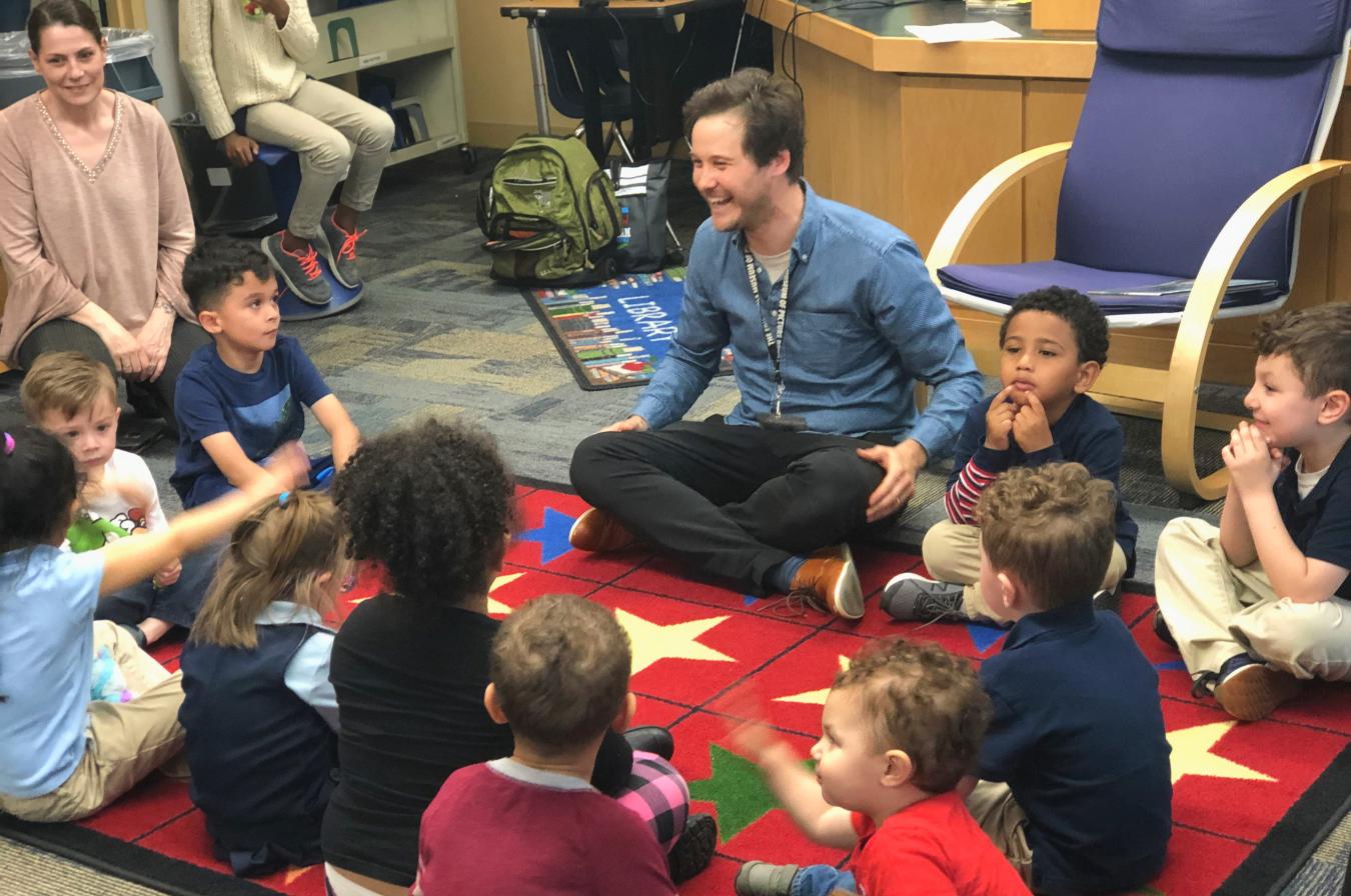 A Carle educator sitting and laughing with children