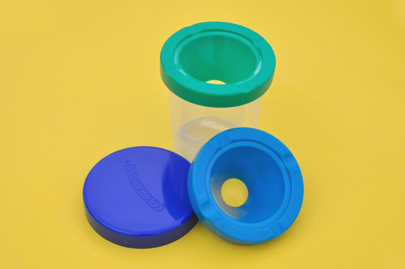 A no-spill cup assembled with a lid and extra top leaning against it.