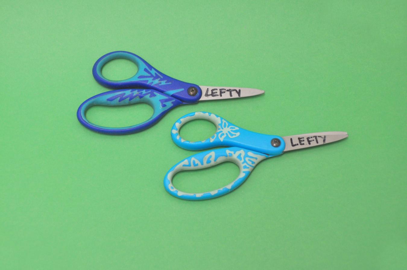 Two lefty scissors next to each other with the word "lefty" written on each scissors' blade.