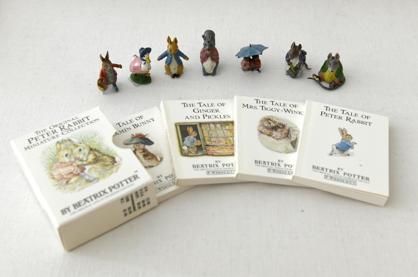 Seven miniature figurines and a small set of Beatrix Potter books.