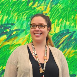 Abigail Scanlon, smiling in front of a green mural painted by Eric Carle.