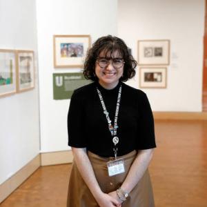 Isabel Ruiz in one of the Museum's galleries with art hanging in the background