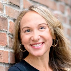 a white woman in a dark shirt, smiling