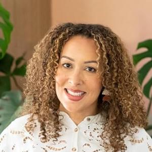 a woman with brown skin and curly hair, smiling