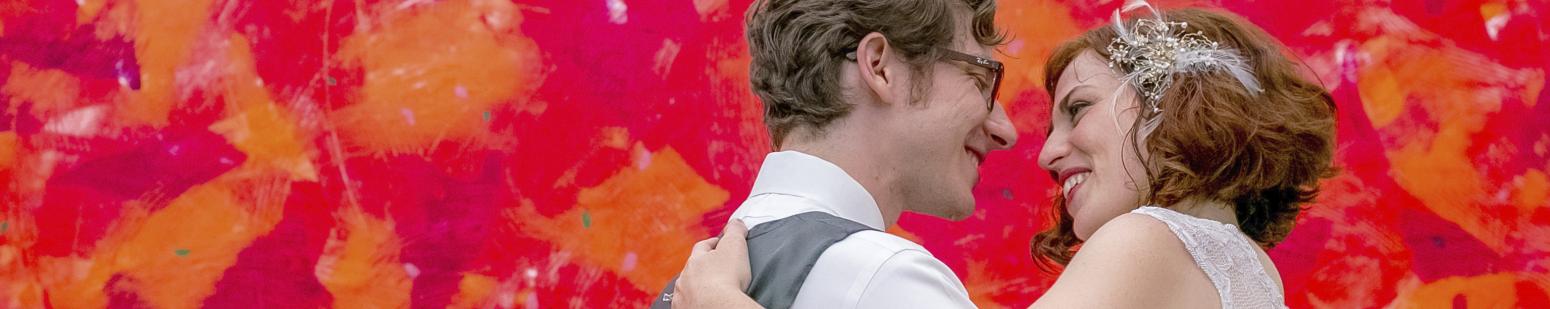 Wedding couple standing in front of a red painting.