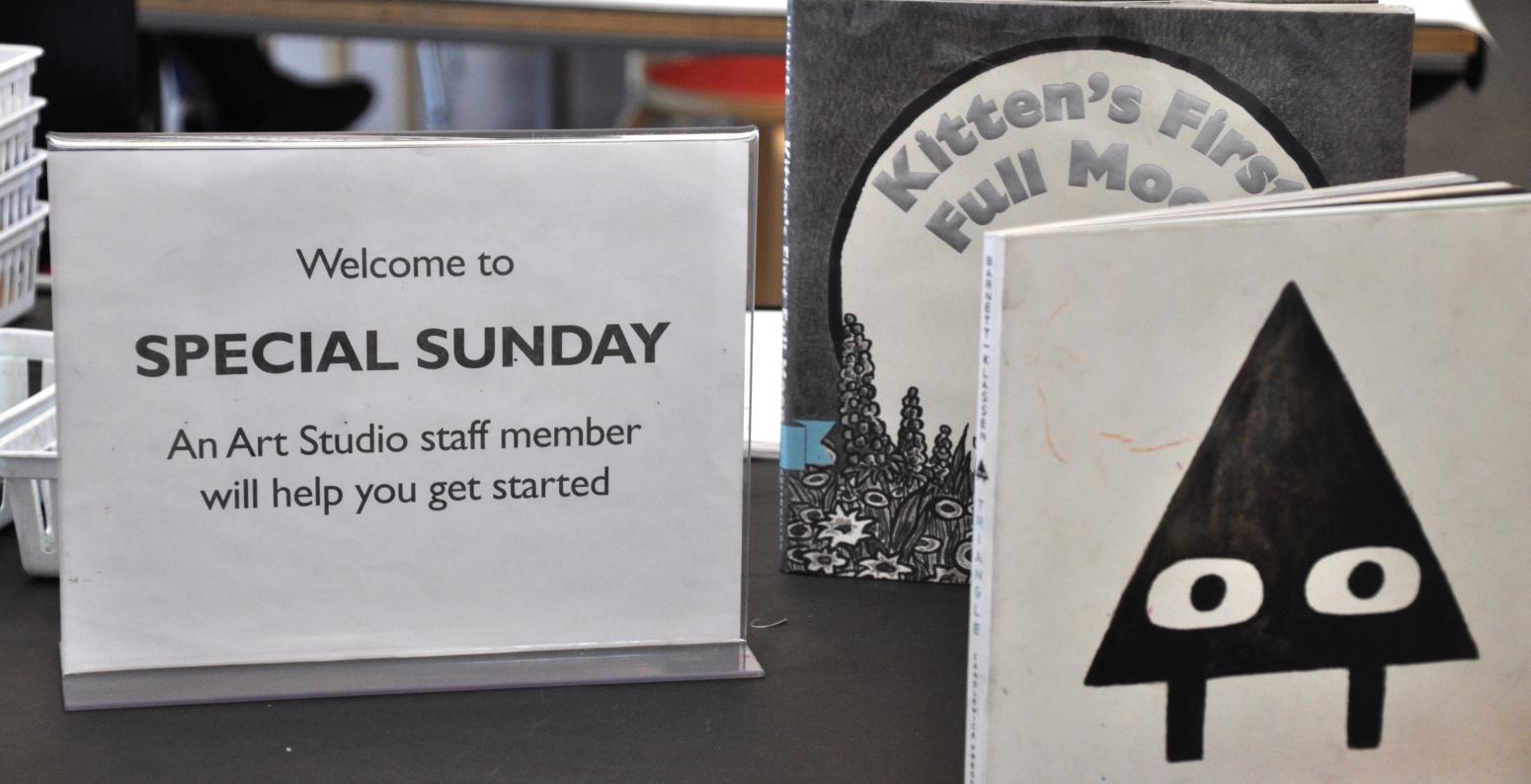 A sign welcoming guests to participate in a Special Sunday project and two picture books, Triangle, and Kitten's First Moon.