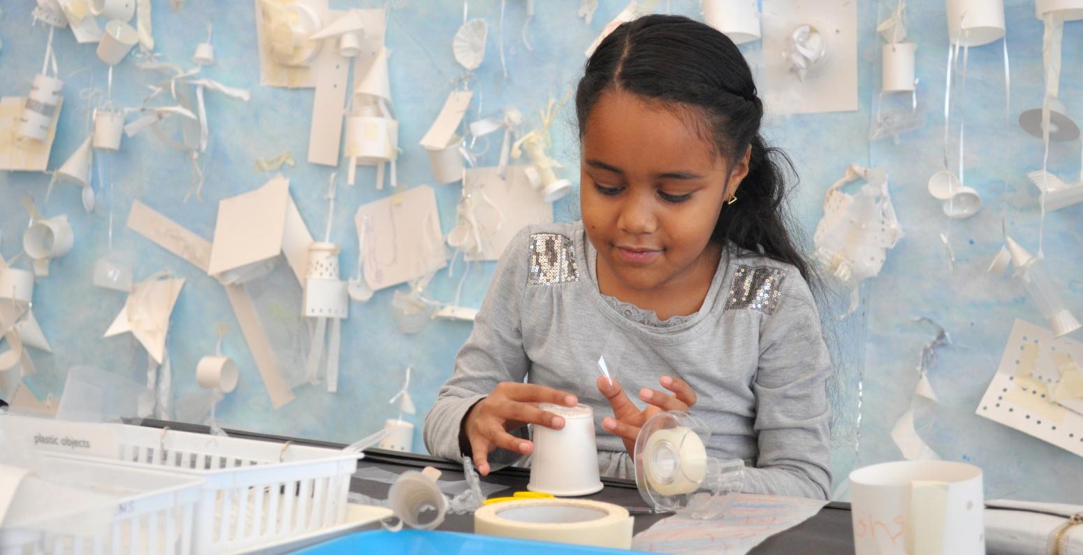 A young child carefully applies tape to their mobile.