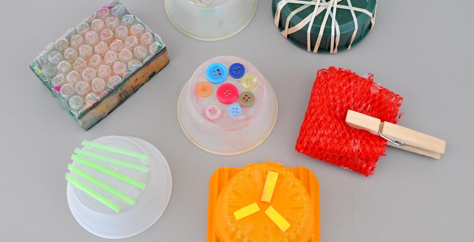 A collection of stamps made from found materials such as bubble wrap, plastic cups, rubber bands, and buttons.