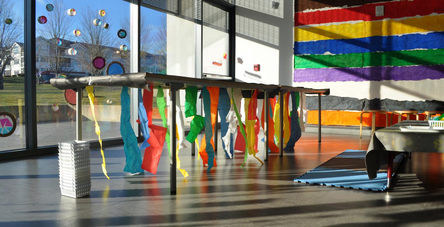 A table in the Art Studio with streamers of colorful tissue paper hanging from underneath the table.