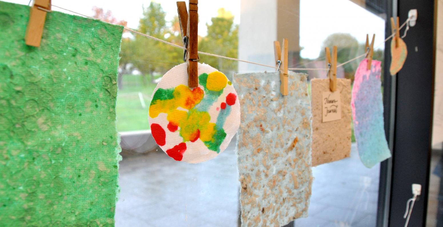 A clothesline with handmade paper clipped to each clothespin.