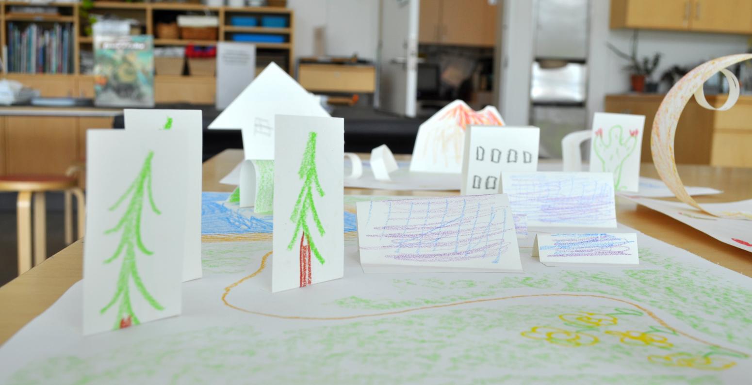 A map drawing with paper trees and bridges standing up on top.