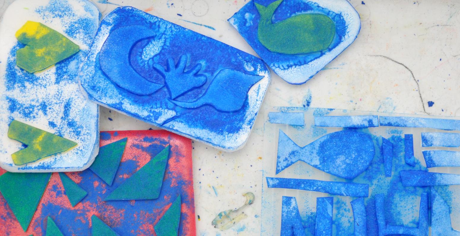 A white basket with five homemade stamps in it, covered in blue paint.