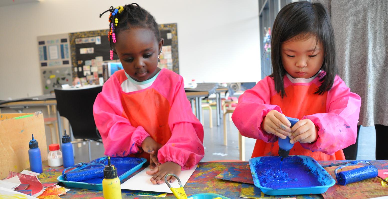 Two young children printmaking with blue paint.