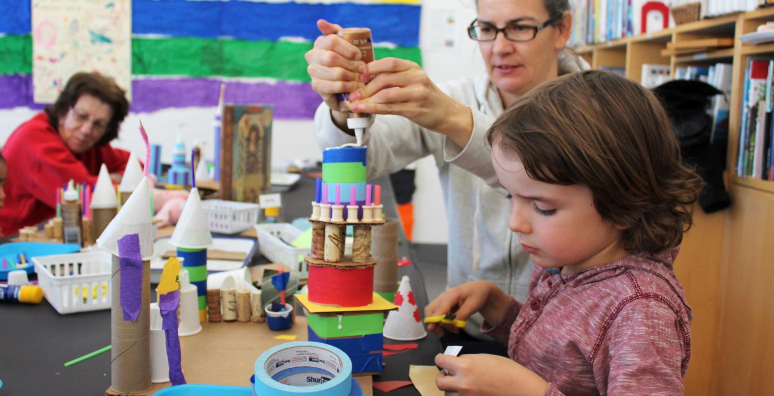 An adult and child working together to construct a tower sculpture.