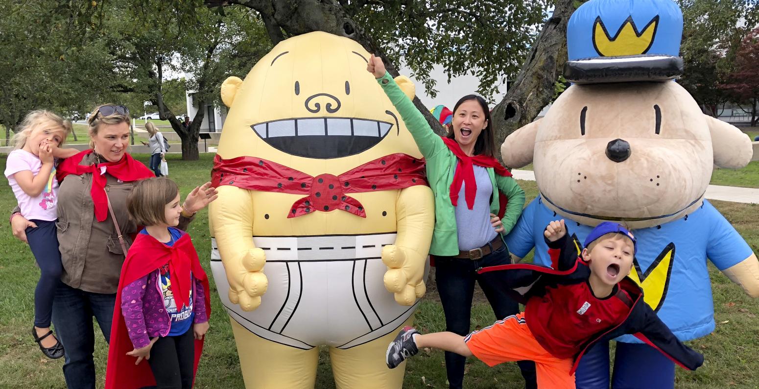 Visitors posing for group photo with Captain Underpants and Dog Man at an event..