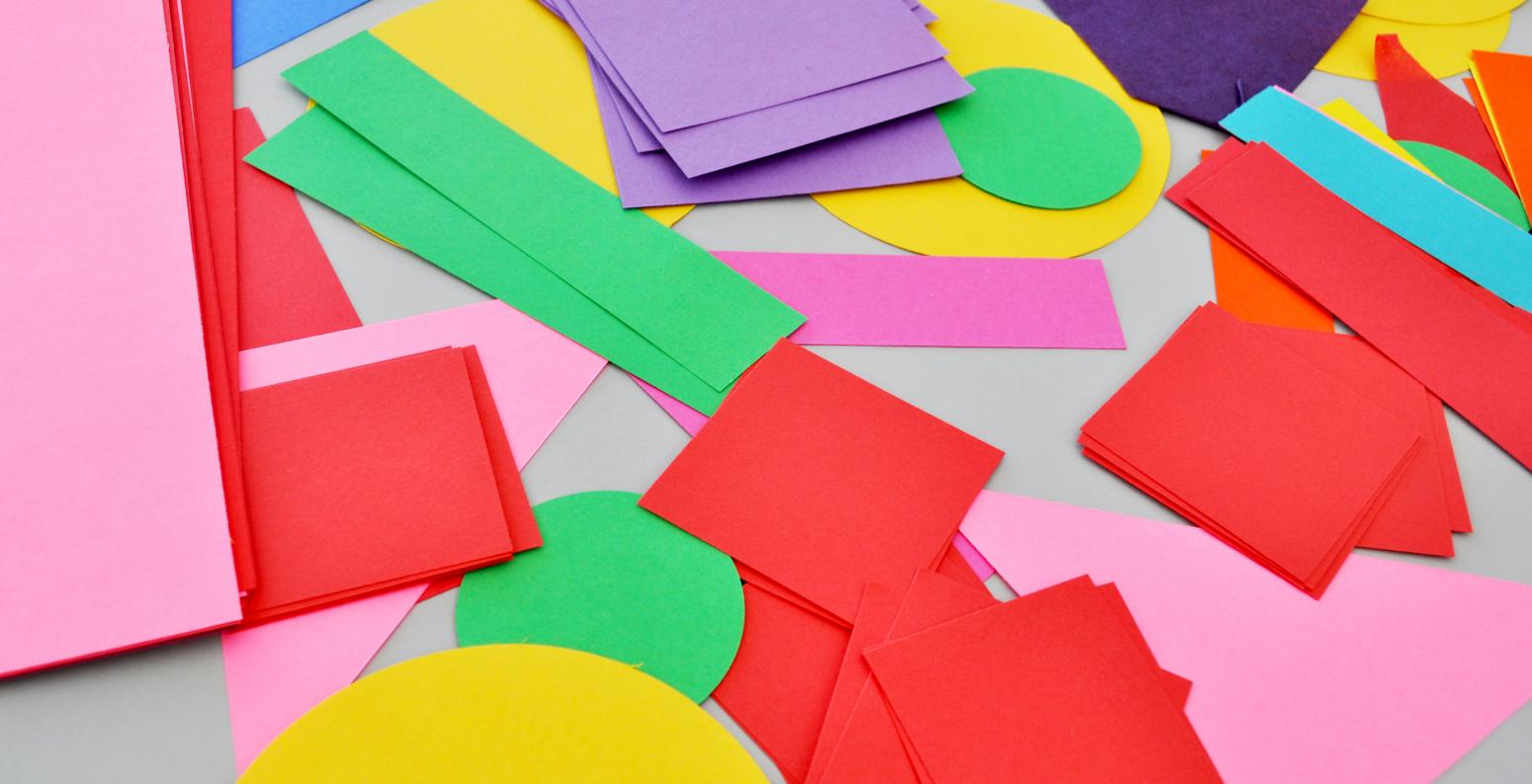 A colorful array of paper shapes including green rectangles, yellow circles, red squares, and pink triangles.