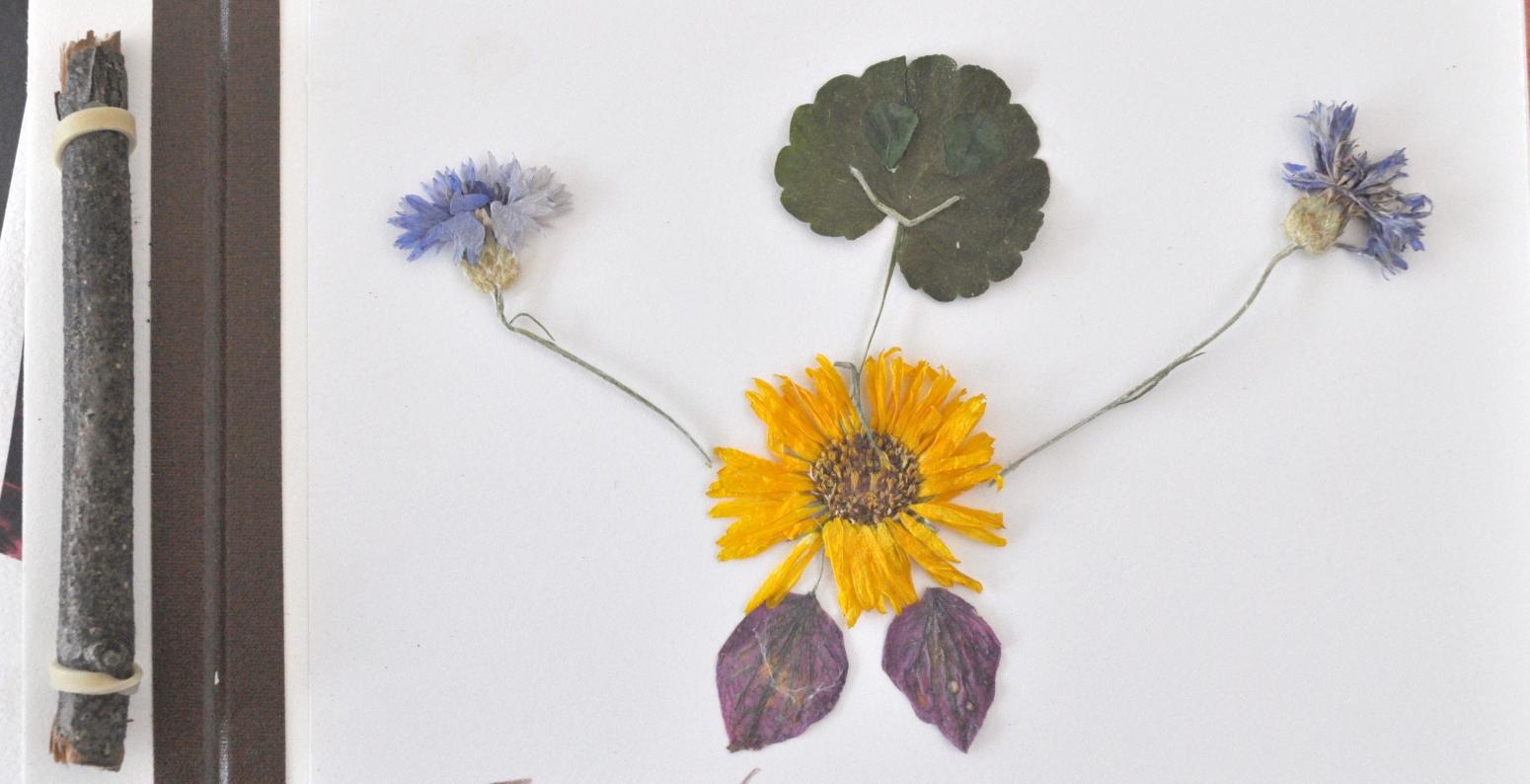 A cover of a handmade book with a person made out of leaves and flowers.