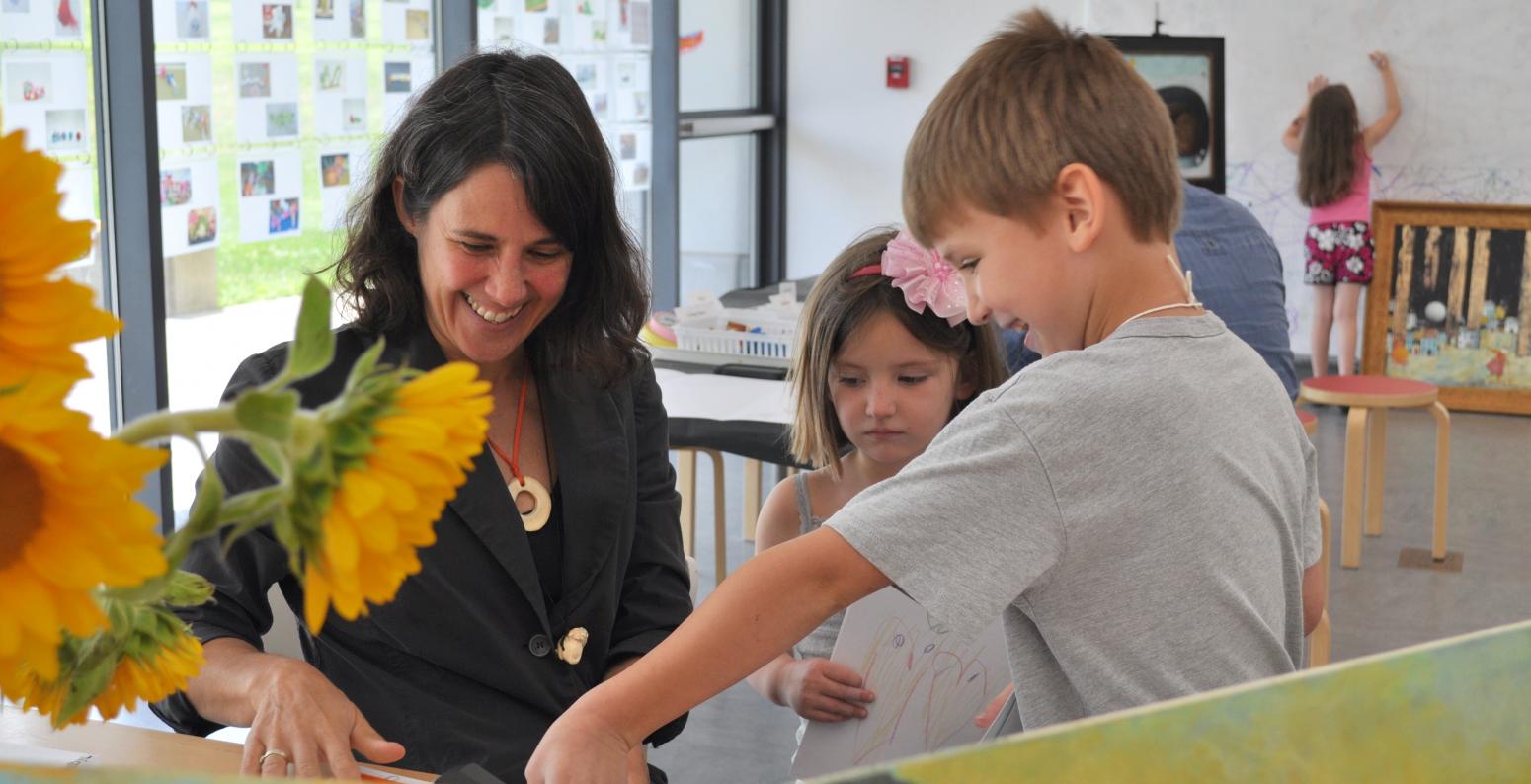 Author/illustrator Pamela Zagarenski smiling and talking with two children in the Art Studio.