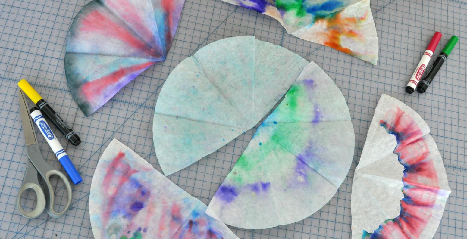 Six coffee filters that have been drawn on with markers then sprayed with, or dipped in, water to make the colors run through the filter.