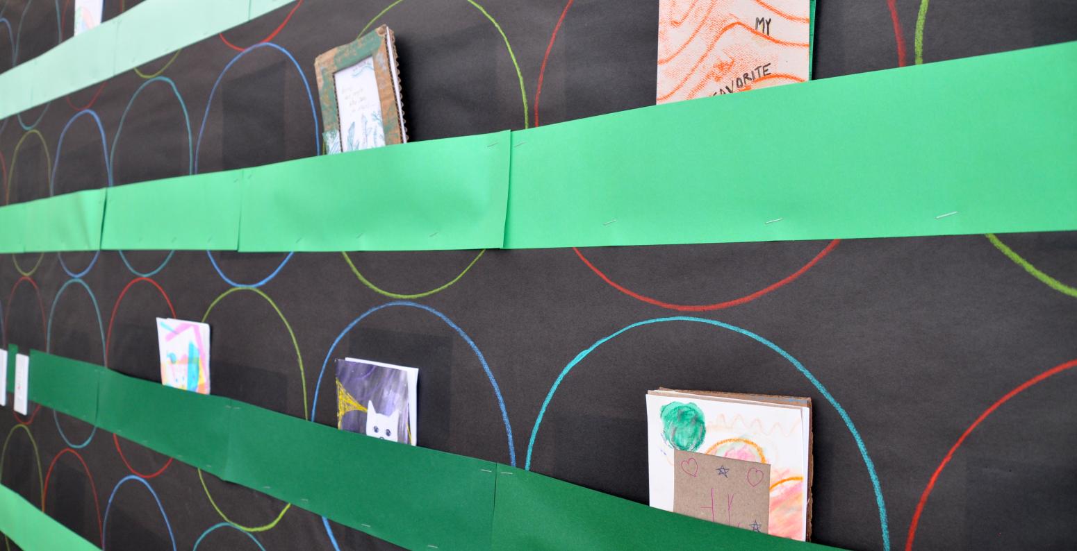 A close-up of the Art Studio bulletin board showing construction paper pockets with accordion fold books inside.