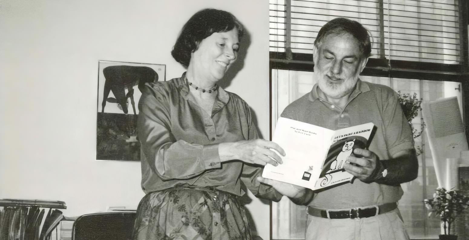 Photograph of two people reading a book together.