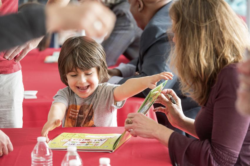 Boy excitedly reading book at signing. 