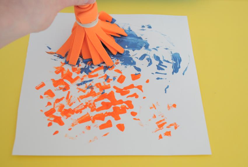 A close-up of the straight edge brush creating orange and blue marks. 