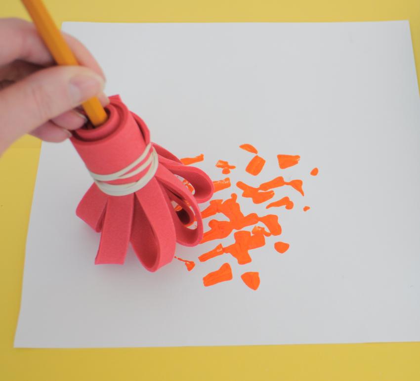 A handmade craft foam brush creating orange dots. 