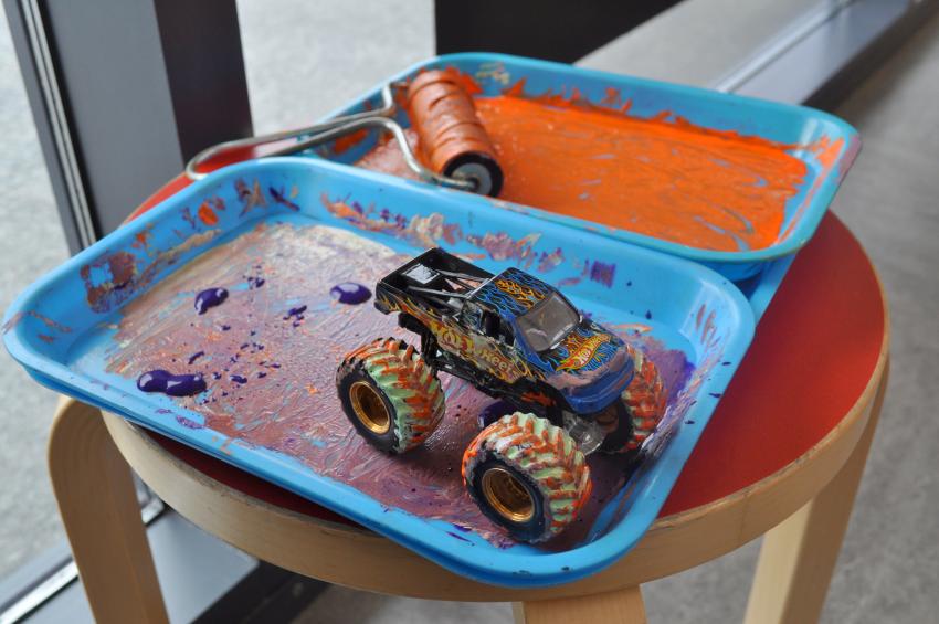 A toy car sitting in a tray of paint.