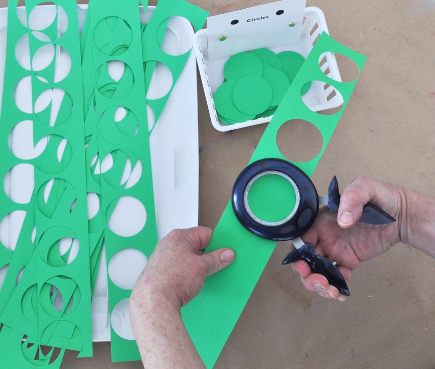 A team member punching out green paper circles 