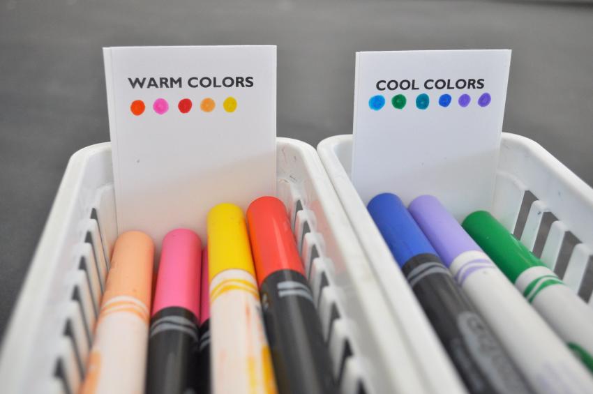 A container of markers with warm colors and a container of markers with cool colors.  