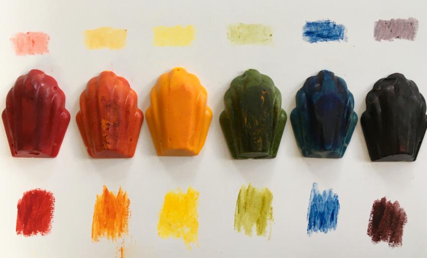 A row of homemade crayons with marks above and below them made by the crayon.