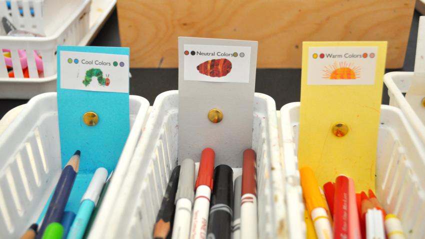 Three baskets with markers divided into warm, cool, and neutral colors, with Eric Carle images on the labels to match the colors.