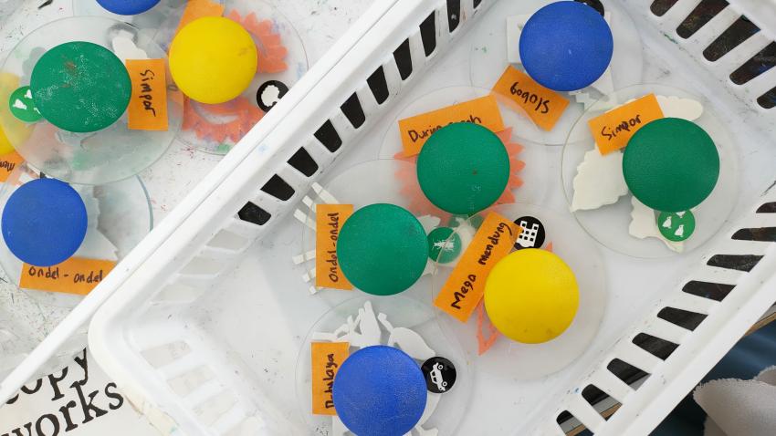 A basket filled with stamp bases that have colorful knobs on the top to hold when stamping.