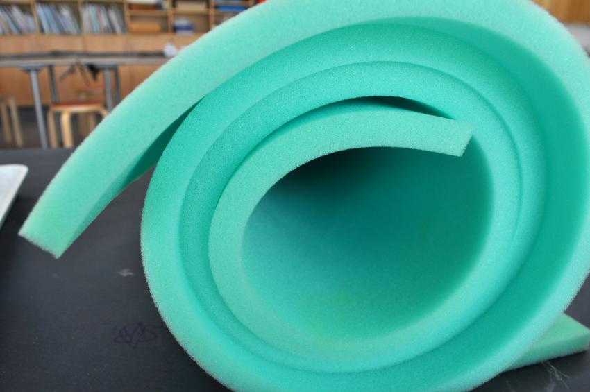 A roll of turquoise upholstery foam on a table. 
