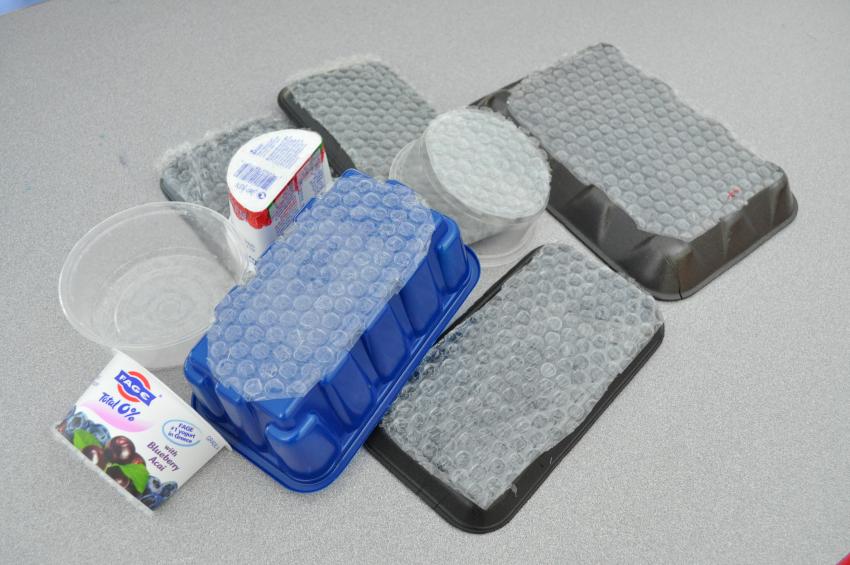 A stack of homemade bubble wrap stamps made with foam trays, plastic containers, and bubble wrap.