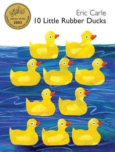 10 little yellow rubber ducks are stacked against a backdrop of blue ocean water.
