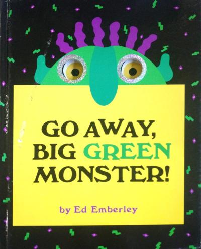 A green monster with a big nose peers over the top of the book with big googly eyes.